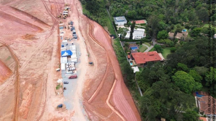 Vista aerea de canteiro de obras com solo exposto a esquerda e area residencial arborizada a direita